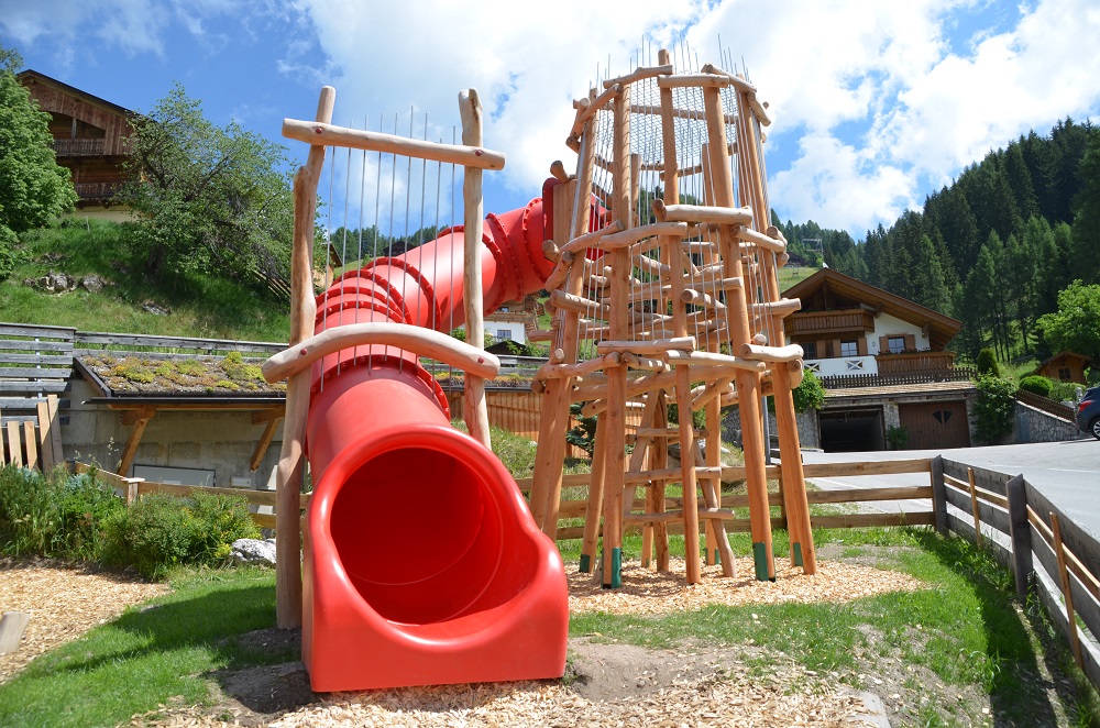 Handgefertigter Kletterturm aus Holz mit roter Röhrenrutsche